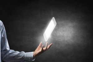 Businessman holding glowing mobile phone on dark background
